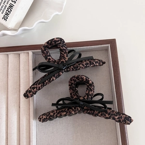 Leopard print hair claw clips with black bows for women displayed in a jewelry box