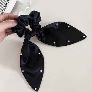 Detail of black satin scrunchie with large bow and elegant faux pearl embellishments