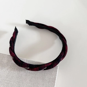 Close-up of red and black plaid braided headband with sparkling rhinestone details