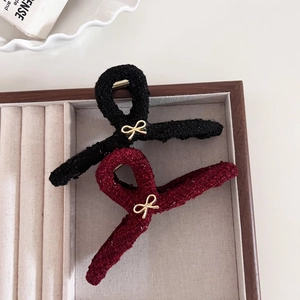 Dettaglio mollette per capelli in tweed rosso e nero con eleganti fiocchi dorati