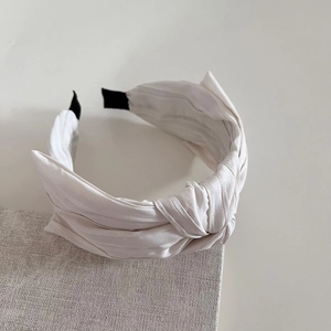 Serre-tête plissé blanc avec nœud en tissu texturé, vue stylée à 45 degrés de l'accessoire
