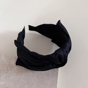 Détail du serre-tête large en tissu noir avec texture satinée et nœud décoratif