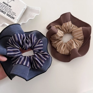 Striped fabric scrunchies in navy blue and brown with soft pleated textures