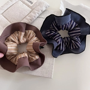 Oversized striped fabric scrunchies in brown and navy blue on a minimalist background