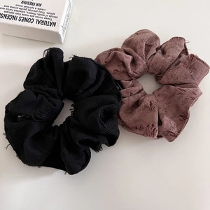 Detail of coffee and black textured fabric scrunchies with vintage frayed edges