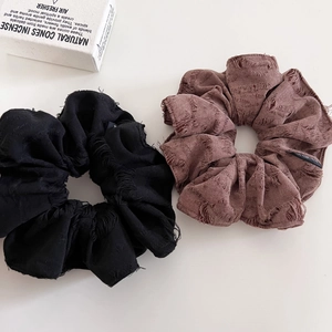 Distressed brown and black fabric scrunchies with bohemian hole detail on white background