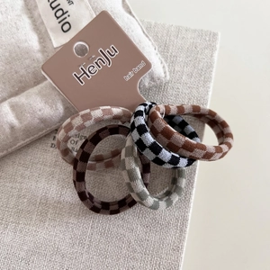Set of five checkered knitted hair scrunchies in earthy tones on a rustic linen background