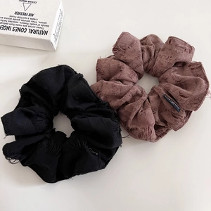 Detailed macro view of vintage distressed fabric scrunchies in black and brown colors