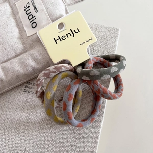 Set of four knitted plaid hair scrunchies with heart patterns on a display card