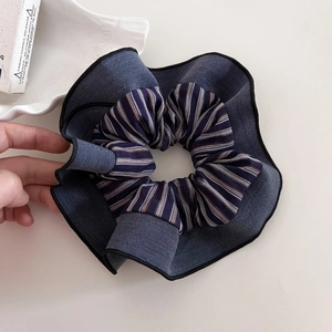 Detail of oversized fabric scrunchie with denim texture and blue striped pattern design