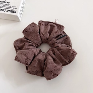Detail of distressed brown scrunchie with frayed edges and For Love woven label tag