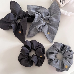 Détail de chouchous gris rayés avec étiquettes métalliques dorées et nœuds chic