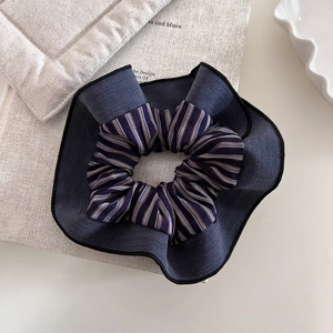 Detailed close-up of striped navy blue patchwork scrunchie on textured background