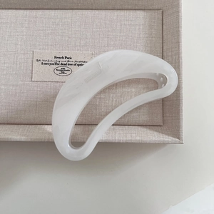 Detail of a large hollowed crescent hair claw clip in creamy white acetate finish