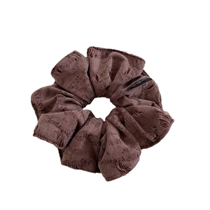 Vintage brown scrunchie with distressed fabric texture and minimalist brand label