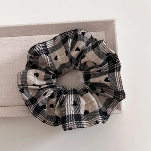 Detail of checkered scrunchie with heart patterns on a display box in a top-down view