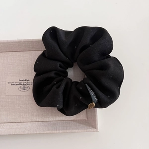 Detail of black polka dot hair scrunchie with Lucky pendant and Blind For Love tag