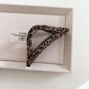 Macro shot of large leopard print hair claw clip on beige fabric tray with metal spring