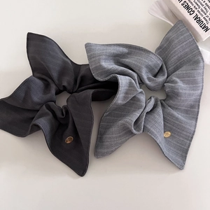 Détail de chouchous en tissu à rayures grises avec élégants logos en métal doré