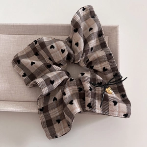 Detail of plaid scrunchie with black flocked hearts, ribbon bow and gold heart pendant