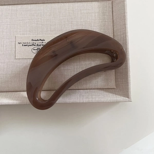 Detail view of large tortoiseshell crescent hair claw with smooth hollowed-out acetate design