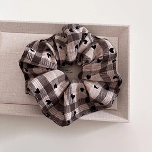 Detailed close-up of brown and beige plaid scrunchie with embroidered black hearts