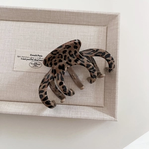 Detailed top view of a large leopard print hair claw clip on a French decor tray