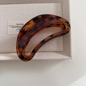 Detail of a large tortoiseshell hair claw clip in amber finish on a textured display tray