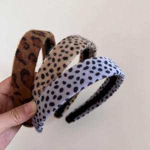 Détail de serre-têtes en velours à motif léopard et à pois violets en main