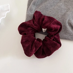 Close-up of a burgundy velvet scrunchie featuring a premium handmade sewing label