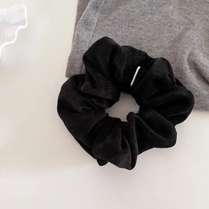 Detailed close-up of a black velvet scrunchie featuring a premium silver metal buckle accent