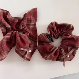Detail of red plaid scrunchies with bow, brown ribbons, and silver charms in retro style