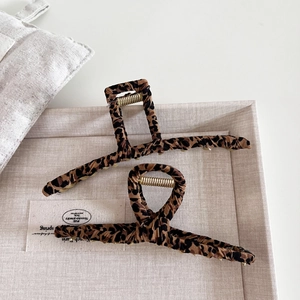 Leopard print claw clip set with gold metal accents on a beige display tray
