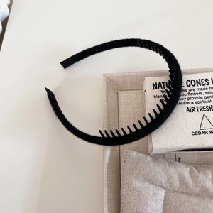 Close-up of black thin headband with inner non-slip teeth and woven yarn texture