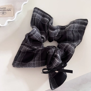 Detail of grey plaid hair scrunchie with black ribbon bow and vintage metallic accents