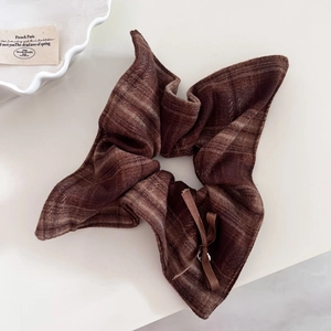 Detail shot of brown plaid scrunchie with elegant ribbon bow and metal charm detail