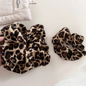 Two-piece set of leopard print satin scrunchies in large and small sizes on white fabric