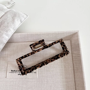 Detail of a large rectangular hair claw clip featuring classic leopard print fabric and metal spring