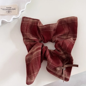 Detail of red plaid scrunchie with bow tie and vintage charm on cream background
