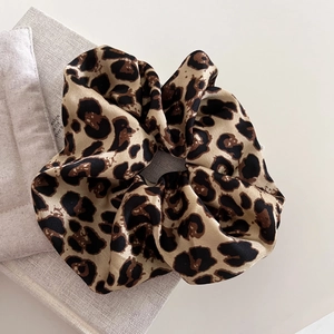 Macro detail of leopard print hair scrunchie with silky satin texture on flat lay background