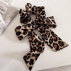 Detail of leopard print satin hair scrunchie with long ribbon bow on white background