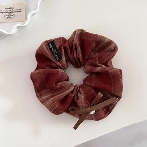 Detail of vintage brown plaid hair scrunchie with silver heart charm and bow ribbon
