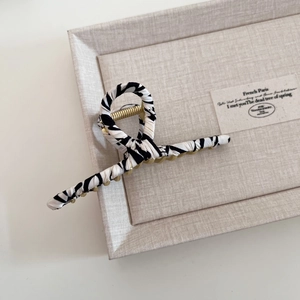Detailed view of metal hair claw clip featuring zebra pattern fabric and golden spring