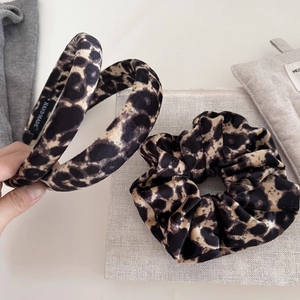 Detailed close-up of velvet leopard print headband and scrunchie set with handmade label