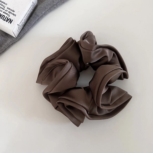 Gros plan d'un chouchou en satin marron chocolat élégant avec des textures de tissu plissées