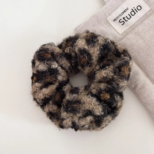 Close-up of leopard print plush scrunchie showing the soft curly texture and elastic design