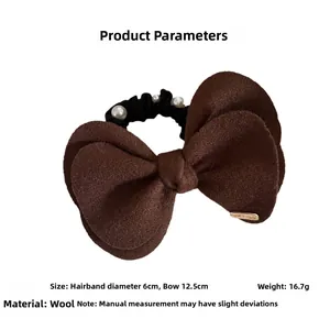 Detail of wool fabric bow hair tie with pearl accent and handmade gold metal tag