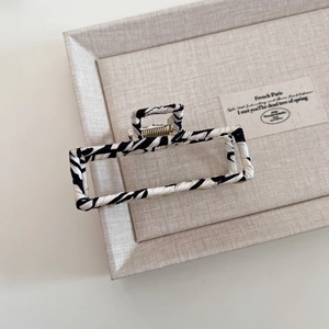 Detail of zebra pattern fabric wrapped hair claw clip on a minimalist display tray