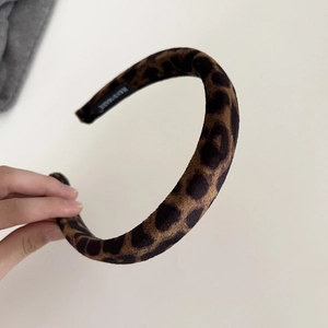 Detailed close-up of handmade leopard print velvet headband with high-end texture label