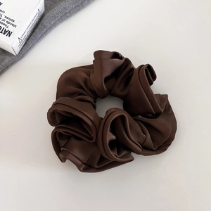 Vue détaillée du chouchou en satin marron foncé avec volants élégants et texture lisse